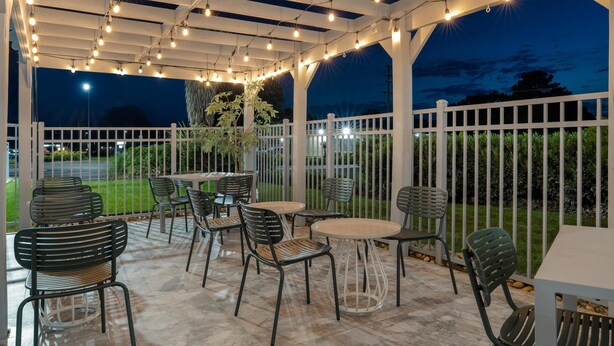 An outdoor patio area with string lights, tables, and chairs.