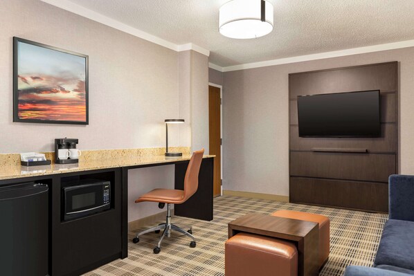 Habitación de hotel con kitchenette, televisor de pantalla plana, sillón cómodo y sofá.