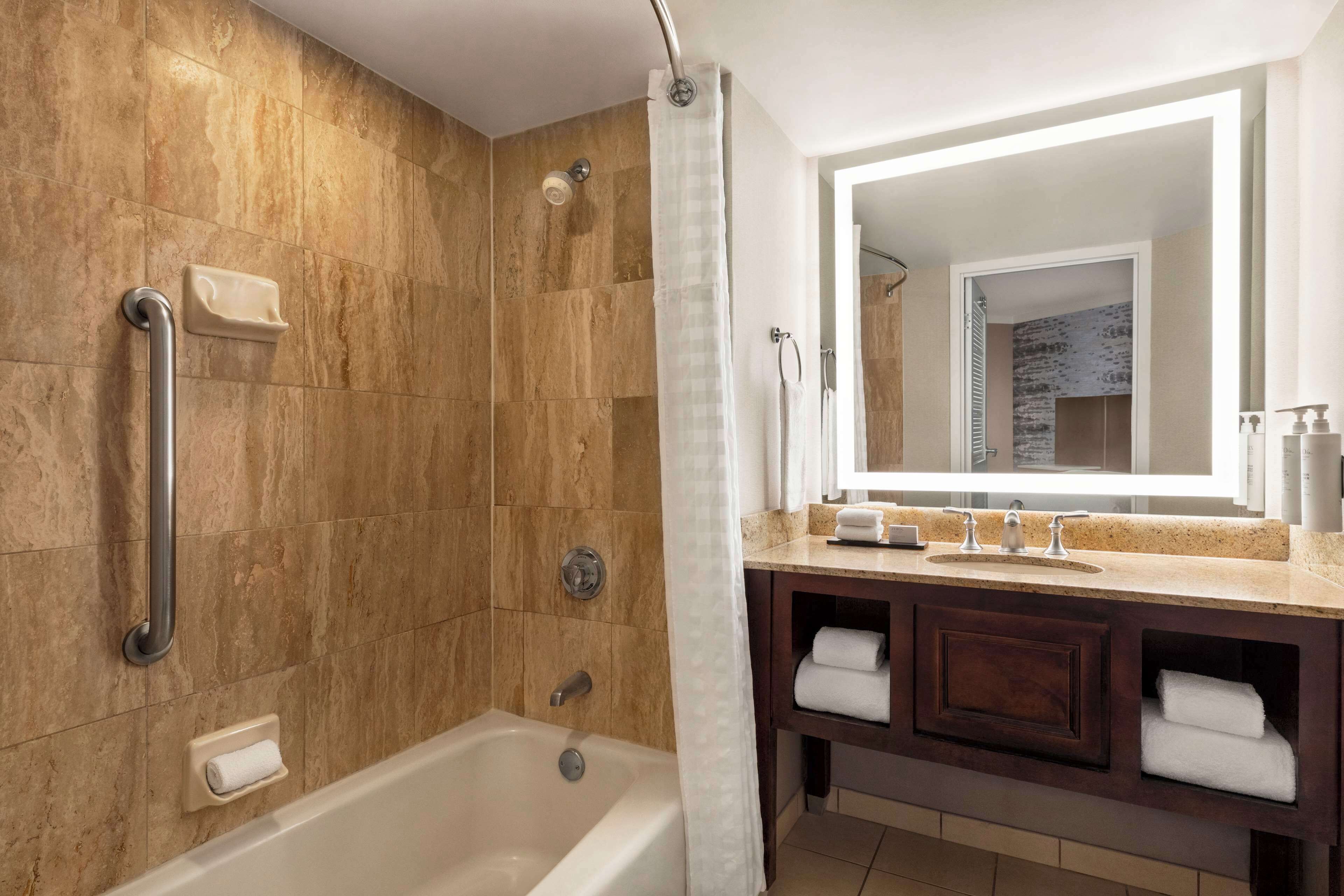 A bathroom with a bathtub, a shower, a vanity with a mirror, and a towel rack.
