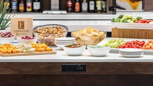Un espace bar avec un assortiment de bouteilles d’alcool et un buffet proposant une variété de fromages, de fruits et de légumes.