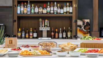 A buffet table with various food items and a bar with multiple liquor bottles in the background.