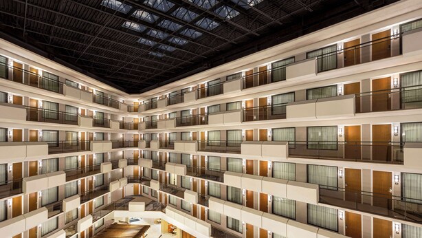L’intérieur d’un hôtel à plusieurs étages, doté d’un atrium central, de balcons et d’un escalier.