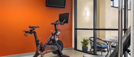 An indoor exercise area with stationary bikes, a treadmill, and a massage chair.