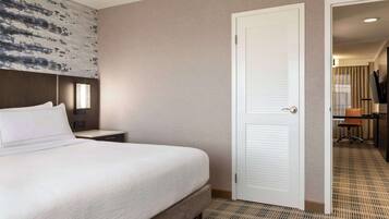 A hotel room with a large bed, a bedside table, a wardrobe, and a door leading to a bathroom.