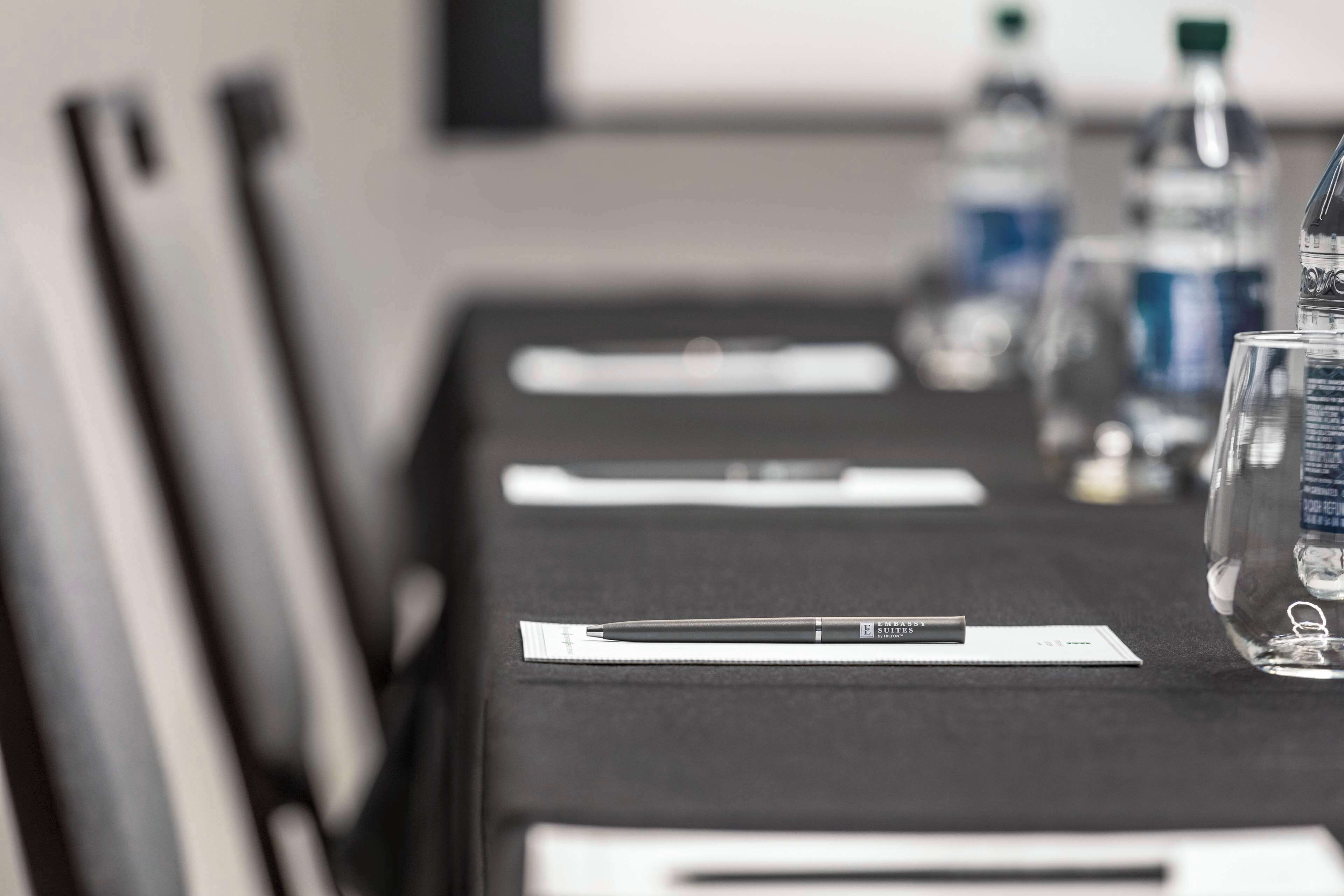 A conference table with water bottles, a pen, and a glass.