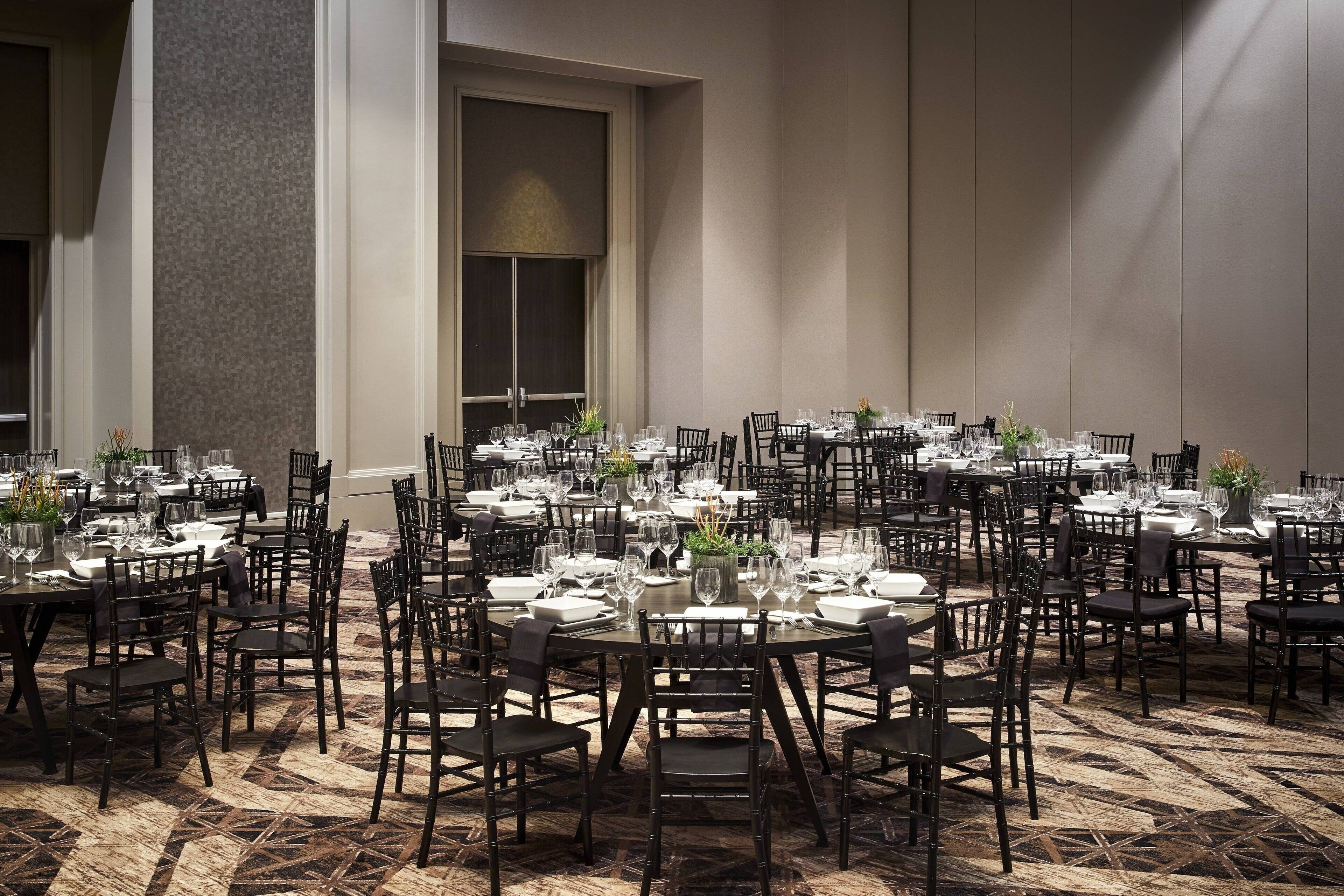 A large dining area with multiple tables set for service, arranged in a spacious room with high ceilings and a patterned floor.