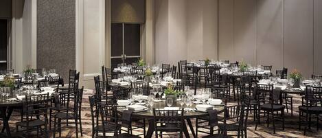 A large dining area with multiple tables set for service, arranged in a spacious room with high ceilings and a patterned floor.