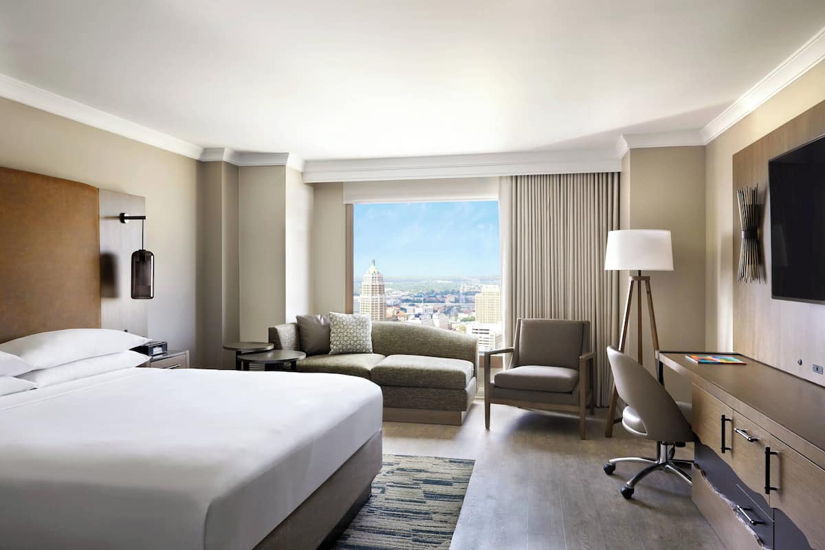 Une chambre d’hôtel avec un grand lit, un bureau, une chaise et une vue sur la ville.