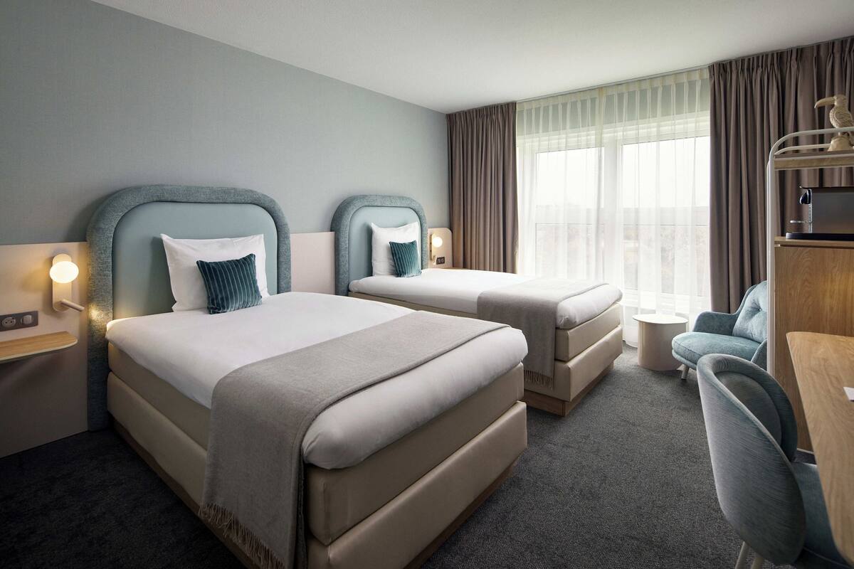 Een hotelkamer met twee bedden, een bureau en een stoel.