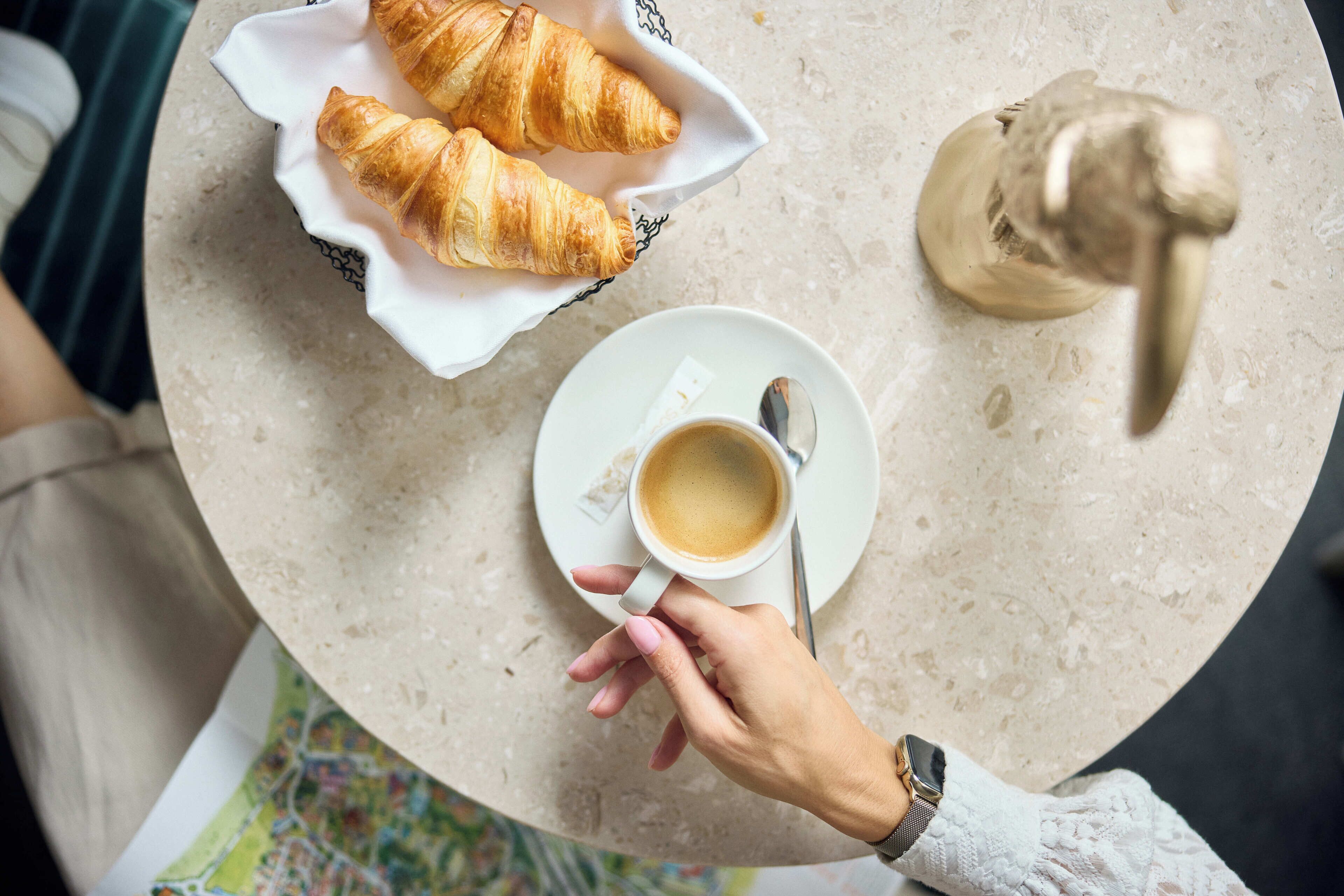 A table with croissants, a cup of coffee, and a spoon.