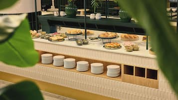 Un buffet proposant une variété de plats et où les assiettes sont empilées.