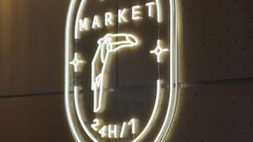 A neon sign with the words "MINI MARKET" and "24H/7" indicating a 24-hour market availability.