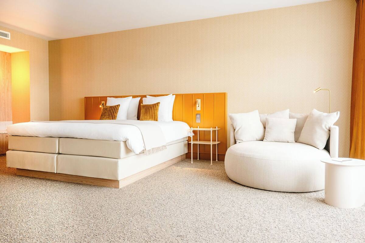 Een moderne hotelkamer met een groot bed, een ronde zithoek en een tafeltje.