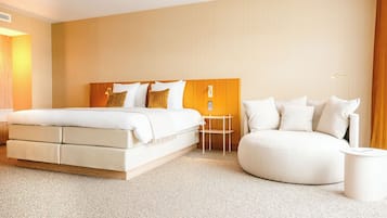A modern hotel room with a large bed, a round seating area, and a small table.