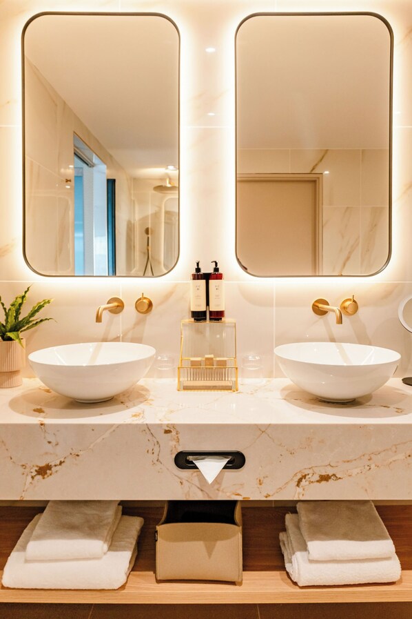 A bathroom with two sinks, a mirror, and a towel rack. - Van der Valk Hotel Paris CDG Airport (Roissy-en-France)