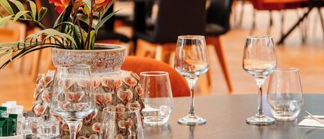 Una mesa de comedor dispuesta con copas de vino, un jarrón con flores y un menú.