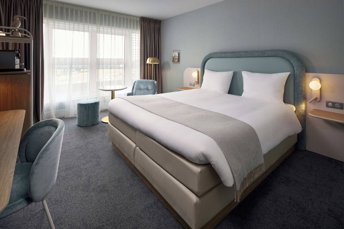 Een hotelkamer met een groot bed, een bureau, een stoel en een klein tafeltje.