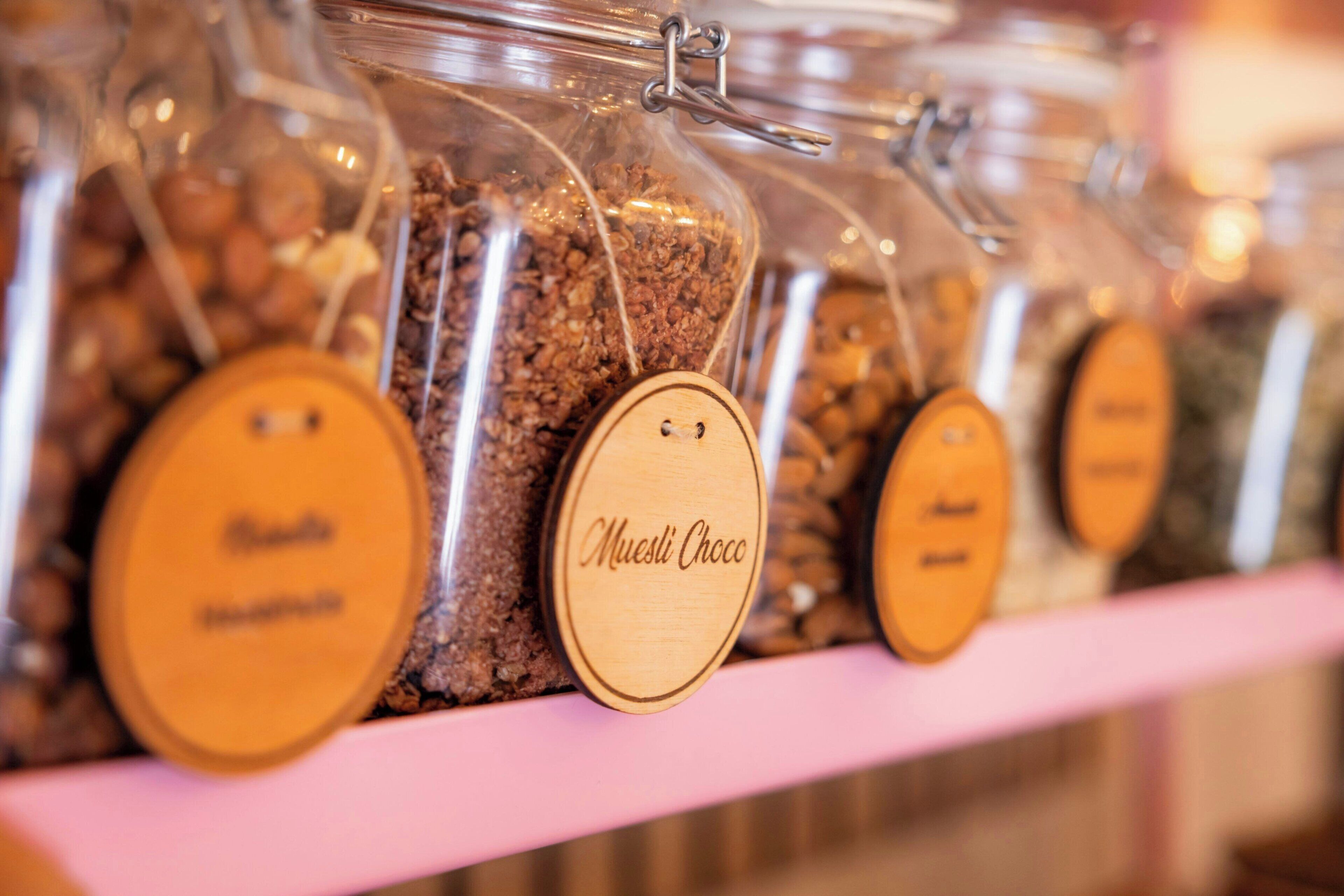 A row of glass jars with wooden lids, each labeled with a different type of chocolate.