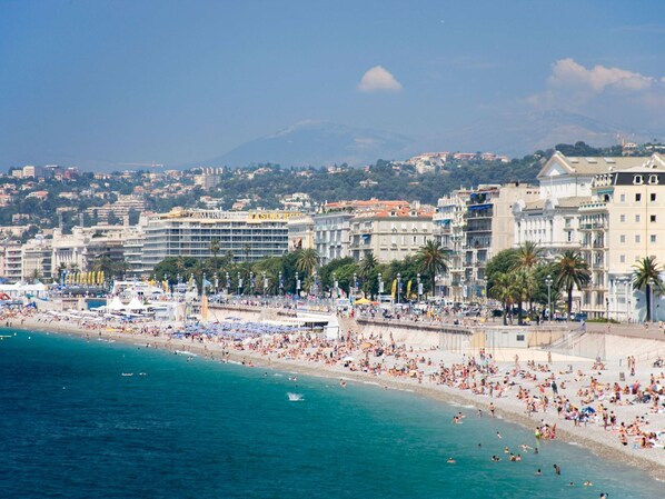 Enjoy the vibrant beachside promenade lined with palm trees and beach umbrellas, offering stunning ocean views.