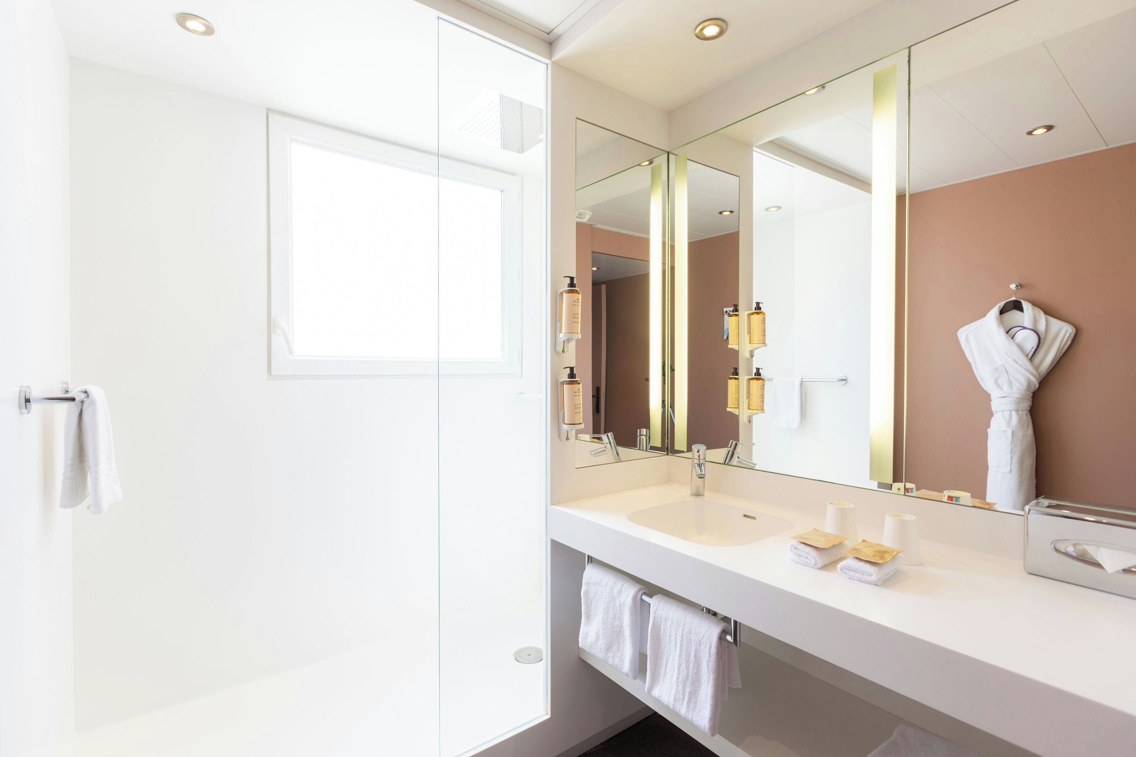 Une salle de bain moderne avec un grand miroir, deux lavabos et un porte-serviettes.