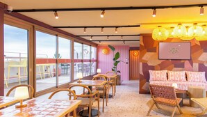Un restaurante con amplios ventanales, mesas y sillas de madera.