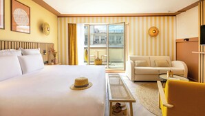 Una habitación de hotel con una cama grande, un sofá, una mesita y un televisor.