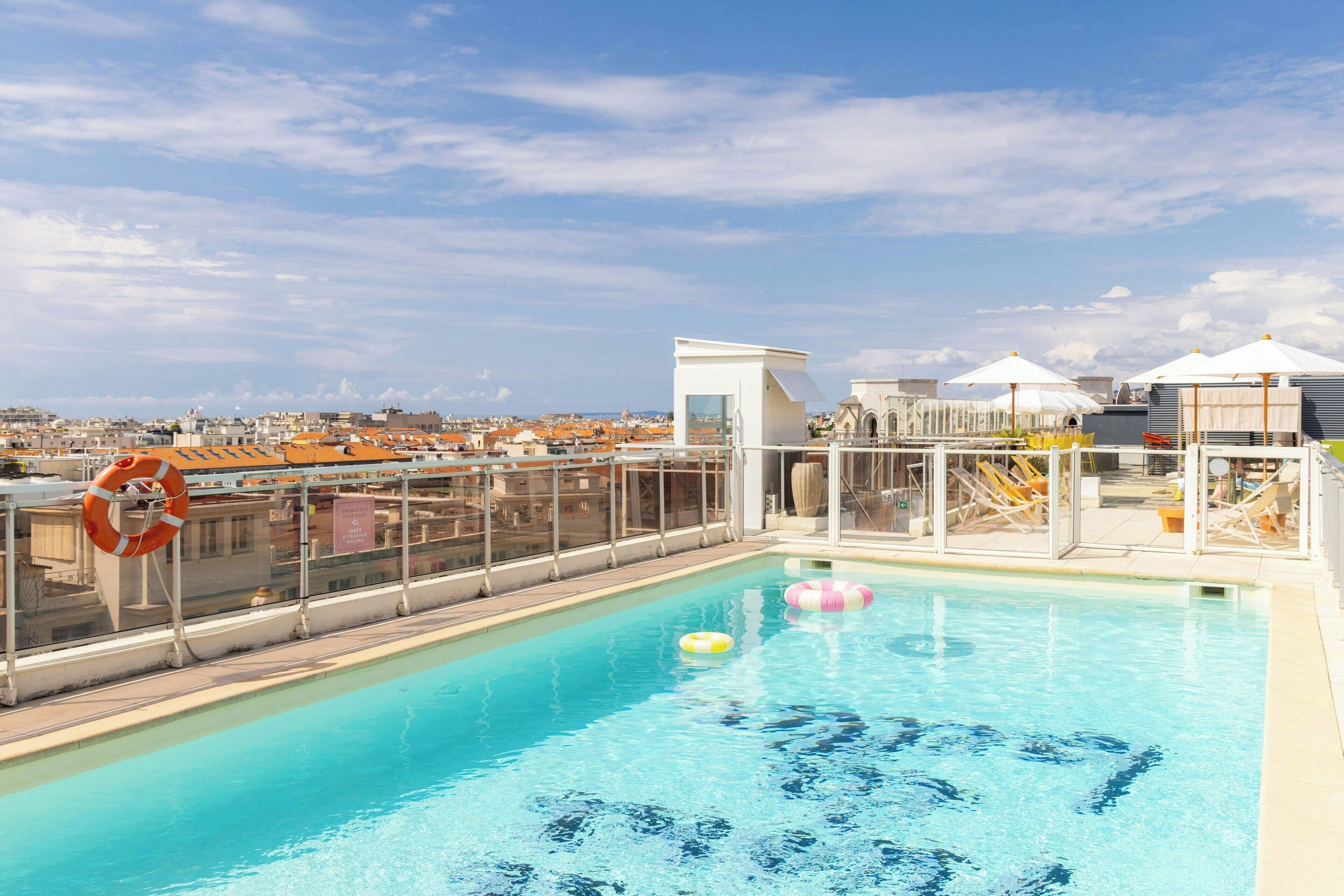 Een buitenzwembad, parasols bij het zwembad en ligstoelen