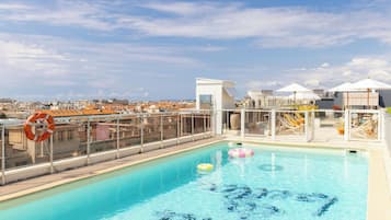 Een buitenzwembad, parasols bij het zwembad en ligstoelen