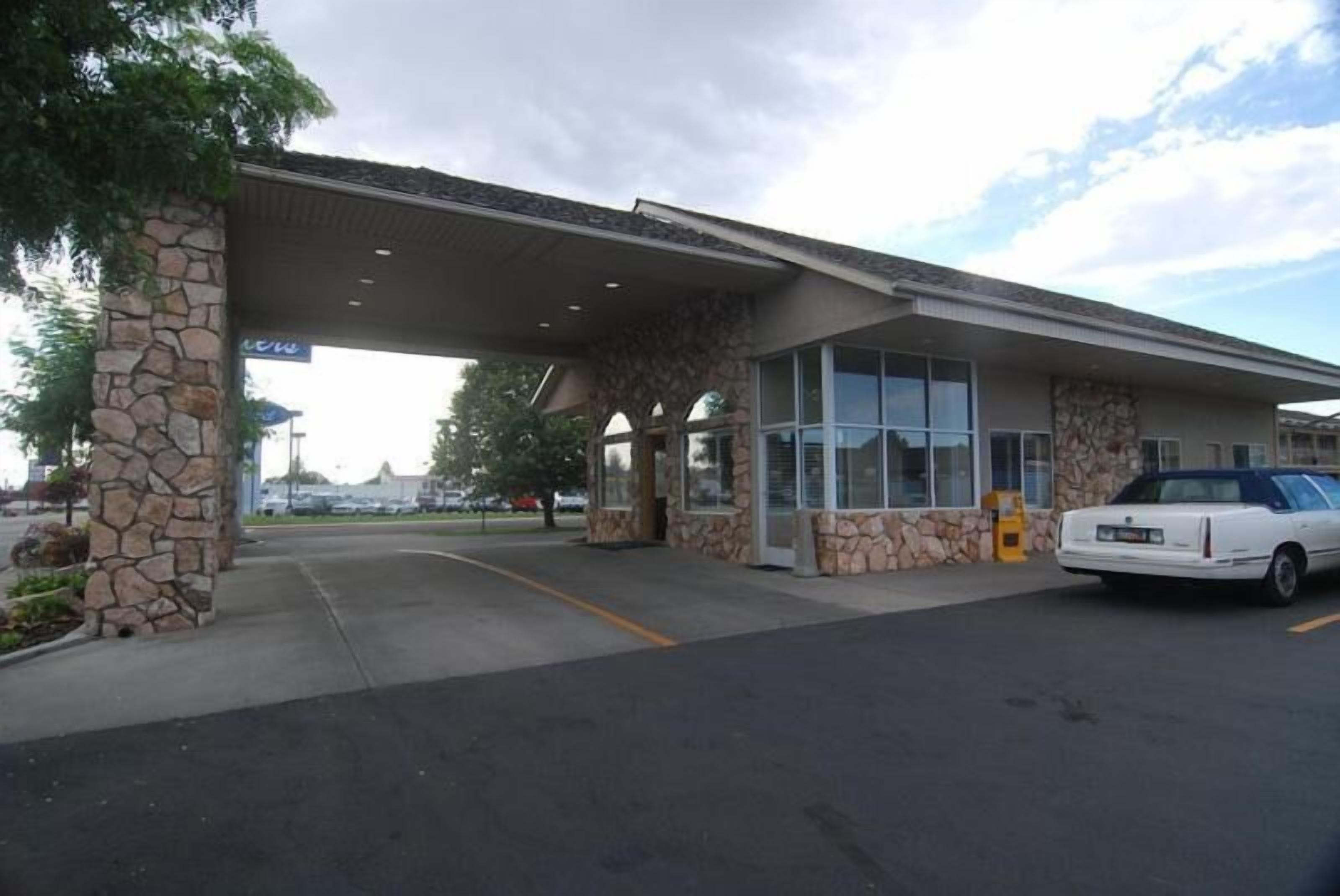 A gas station with a canopy, stone pillars, and a white car parked inside.