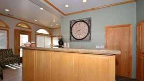 A kitchen with wooden cabinets, a granite countertop, and a wall clock.