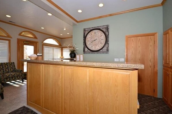 A kitchen with wooden cabinets, a granite countertop, and a wall clock. - Econo Lodge Inn & Suites Vernal near Dinosaur Monument (Vernal)