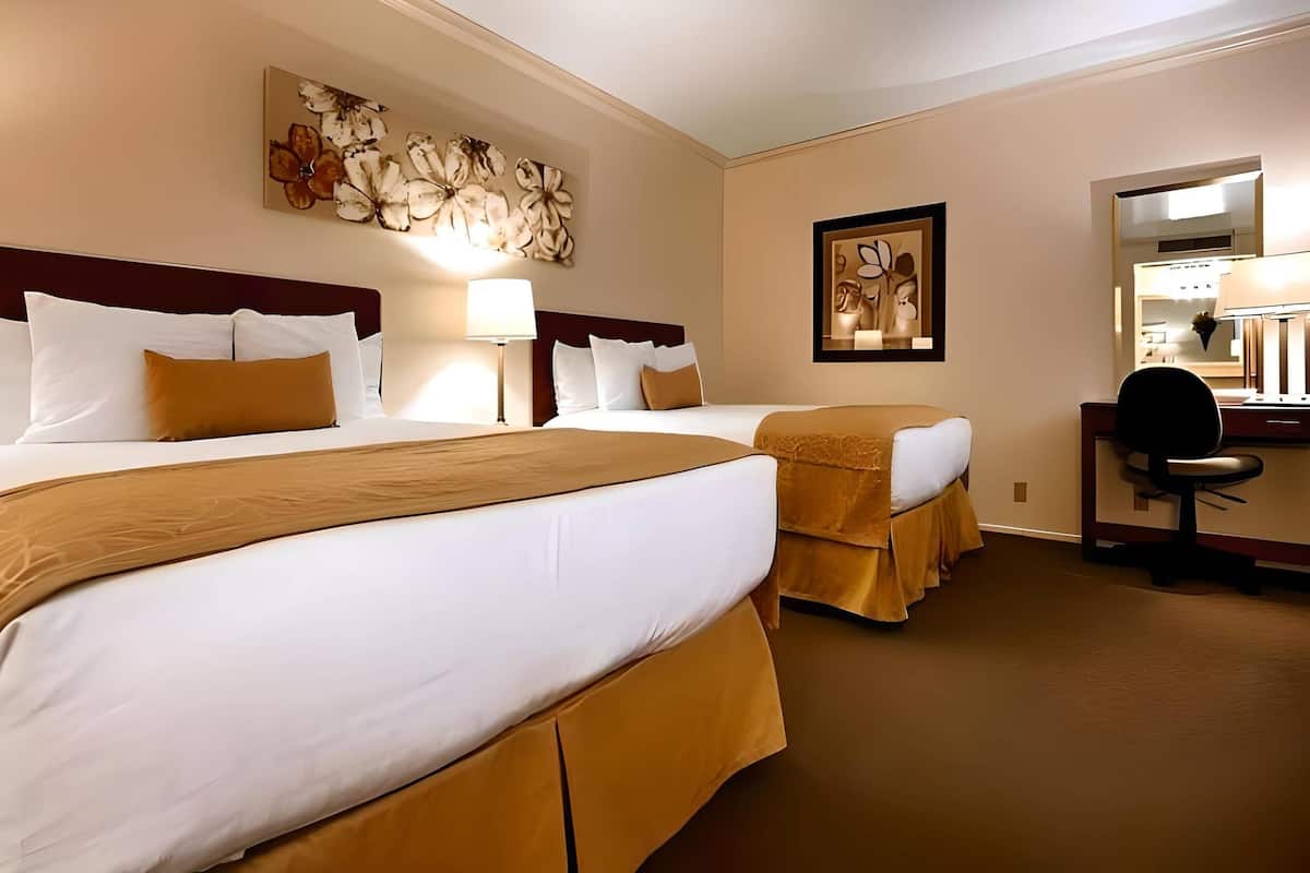 Une chambre d’hôtel avec deux lits, un bureau et une chaise.