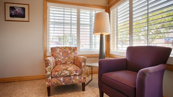 A room with a floral armchair, a purple armchair, and a lamp near a window with blinds. - Econo Lodge Inn & Suites Vernal near Dinosaur Monument (Vernal)