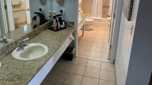 Une salle de bain équipée d’un lavabo, d’un miroir, d’un porte-serviettes et d’une zone douche.