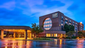 A hotel with a prominent circular window, a brick facade, and a well-lit entrance. - Four Points by Sheraton Milwaukee North Shore (Milwaukee)