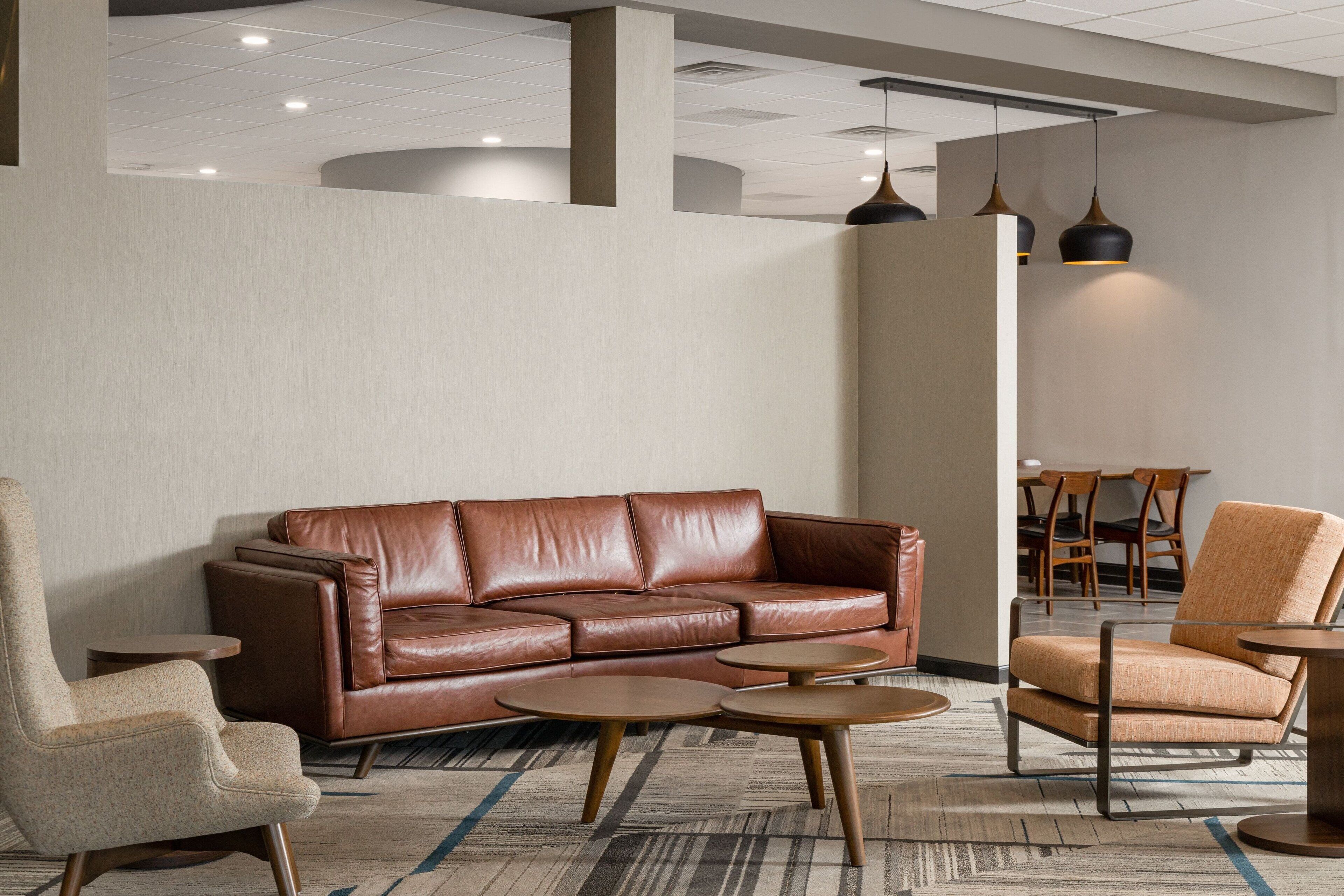 Un hall d’entrée moderne avec un canapé en cuir marron, un tapis à motifs et une table basse en bois.