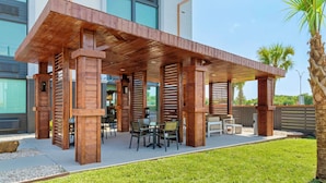 A covered outdoor patio with wooden beams and a table with chairs. - Best Western Corpus Christi Airport Hotel (Corpus Christi)