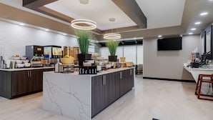 A modern kitchen with a marble island, dark wood cabinets, and a central island with potted plants. - Best Western Corpus Christi Airport Hotel (Corpus Christi)