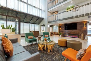 Een ruime lobby met een hoge plafond, een centraal zithoek met een glazen salontafel, en een open haard.