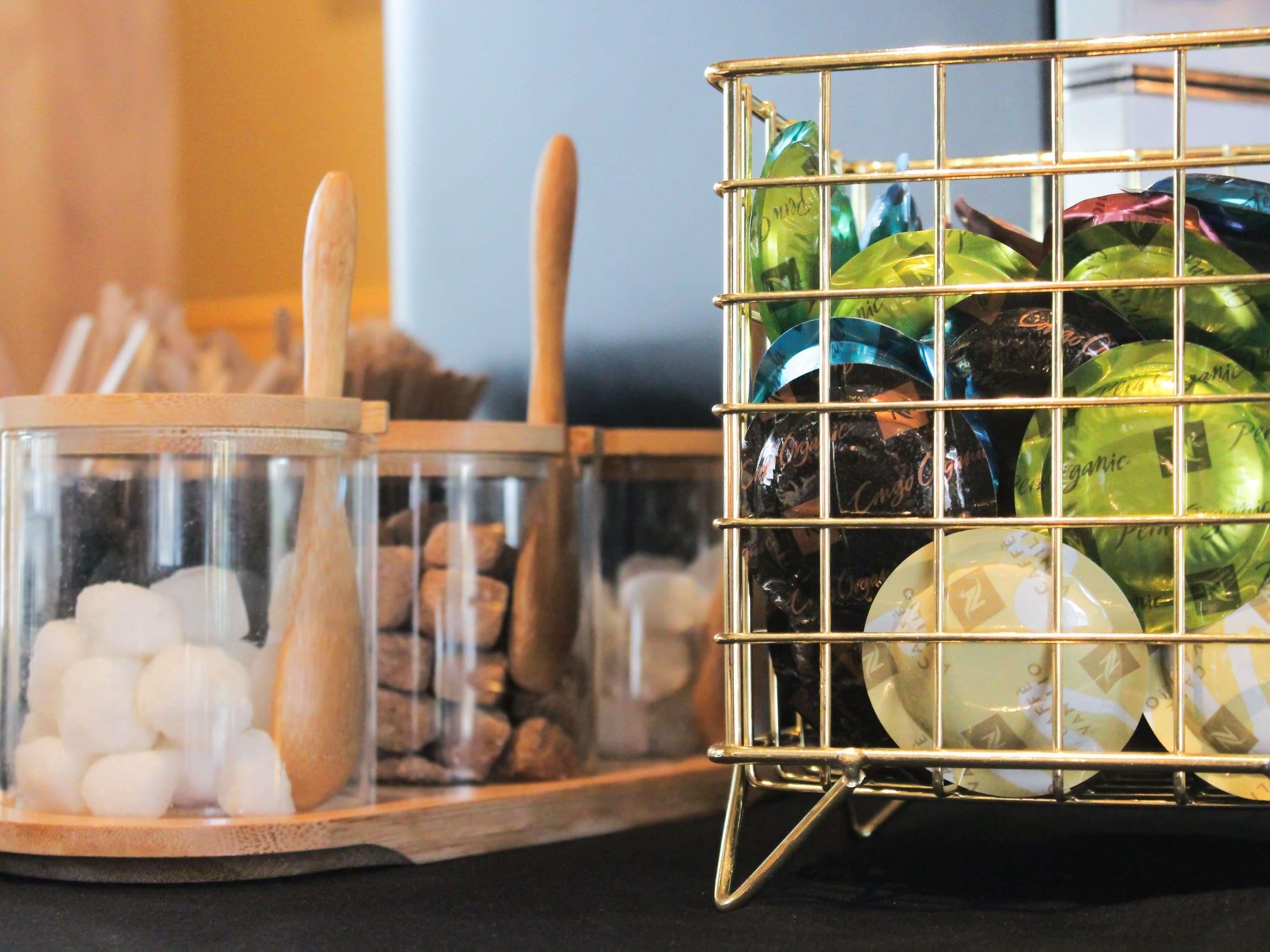 A glass container with white spherical objects and a metal basket with green and blue jars.