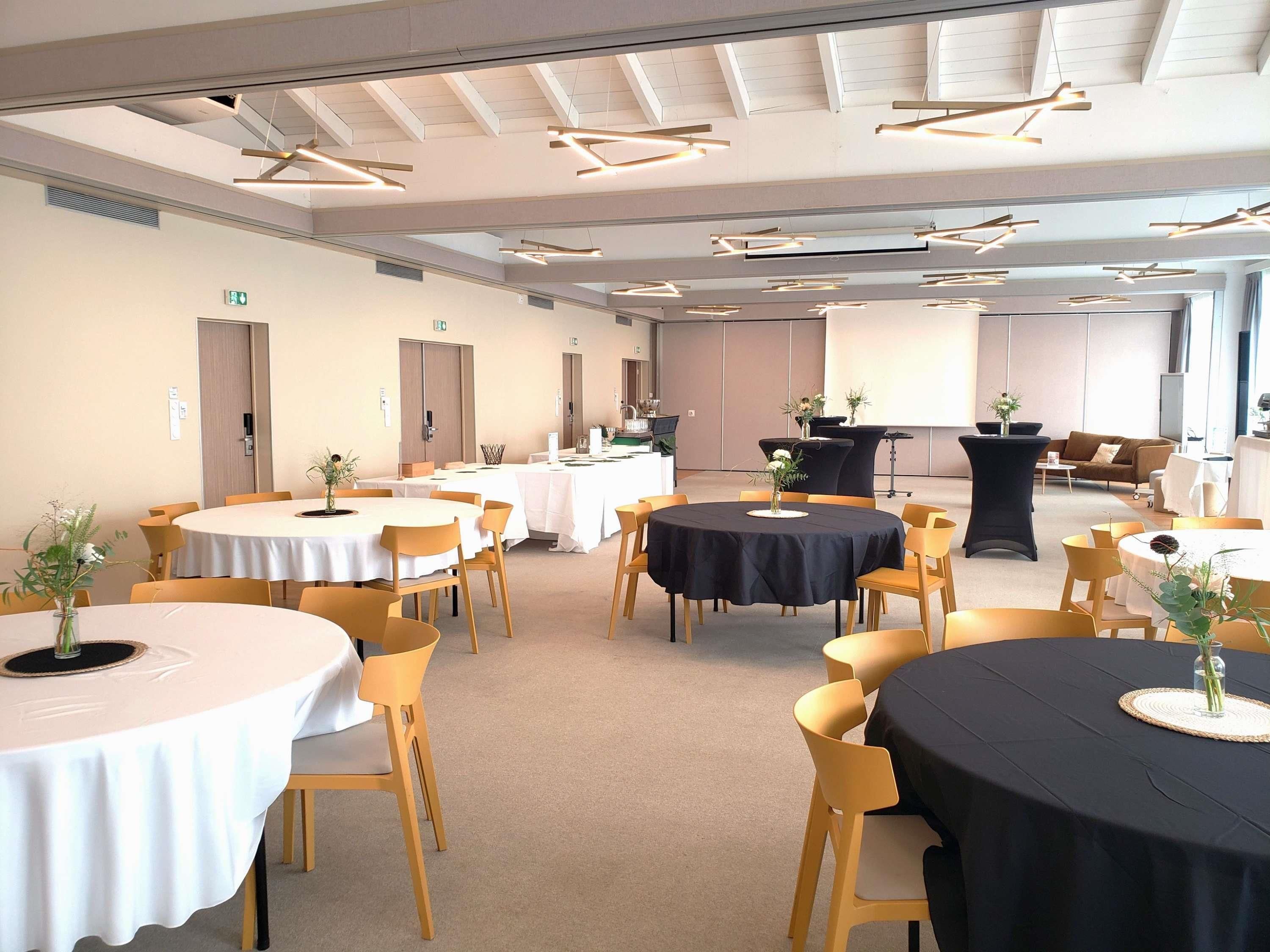 A conference room with multiple tables, chairs, and ceiling lights.