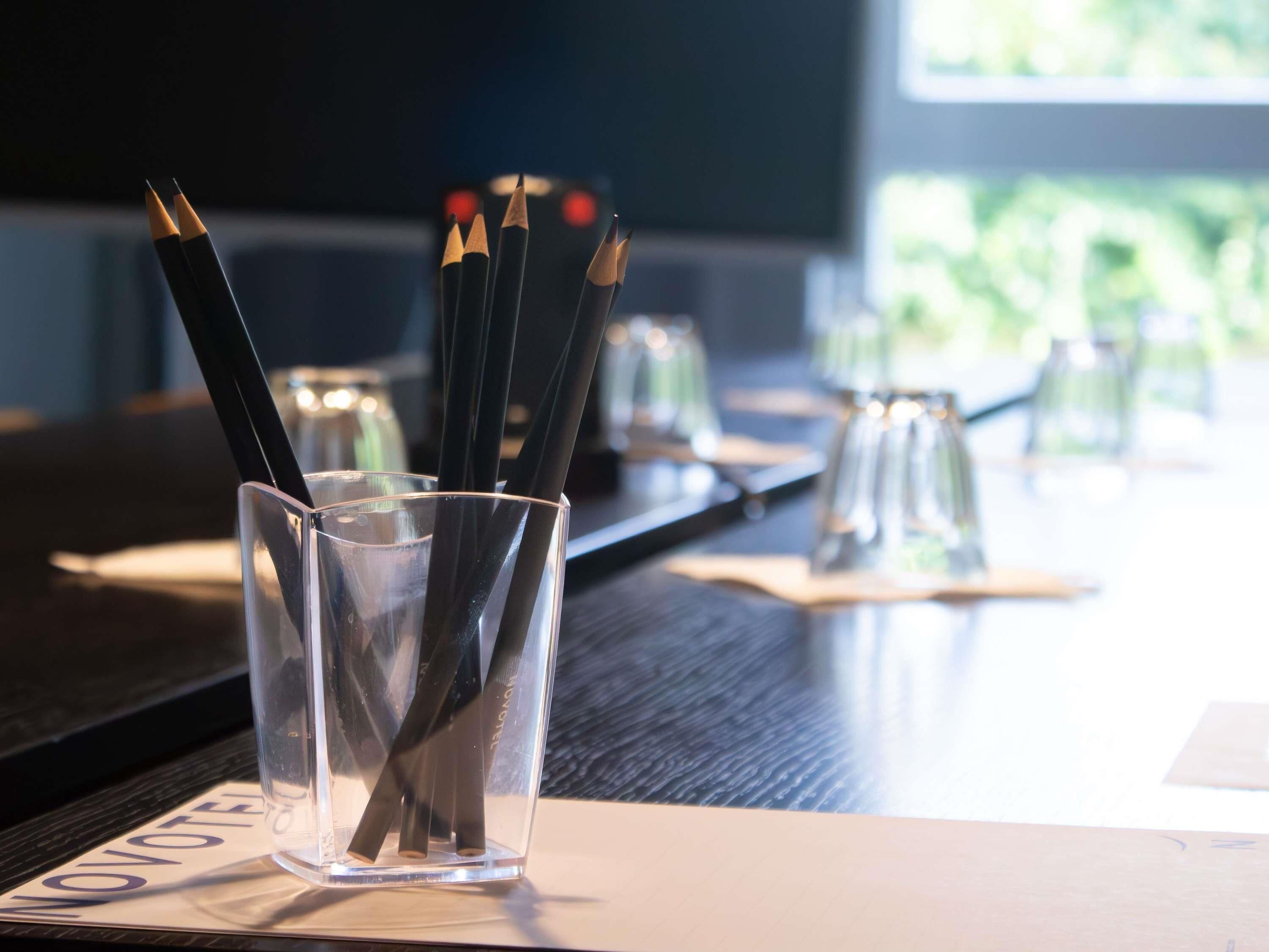 Un recipiente de vidrio con lápices sobre una mesa.