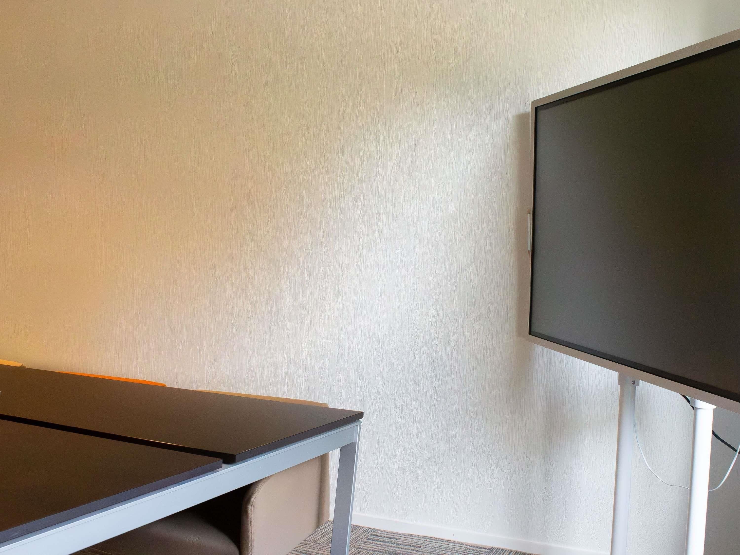 A room with a flat-screen TV, a desk, and a chair.