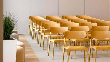 A row of yellow chairs arranged in a semi-circle facing a white wall.