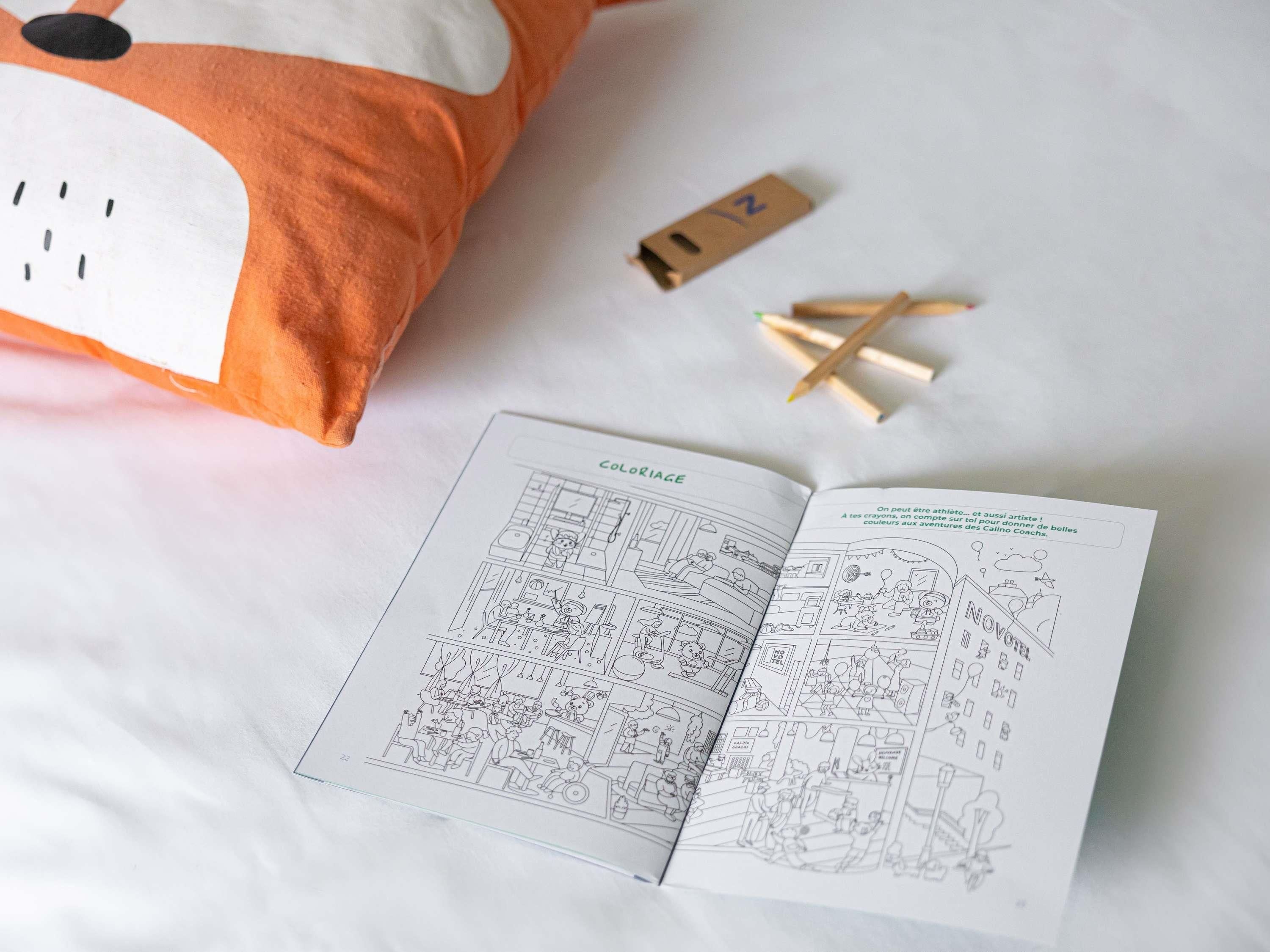 A bed with a pillow, a book, and pencils on a white surface.