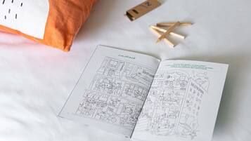 A bed with a pillow, a book, and pencils on a white surface.