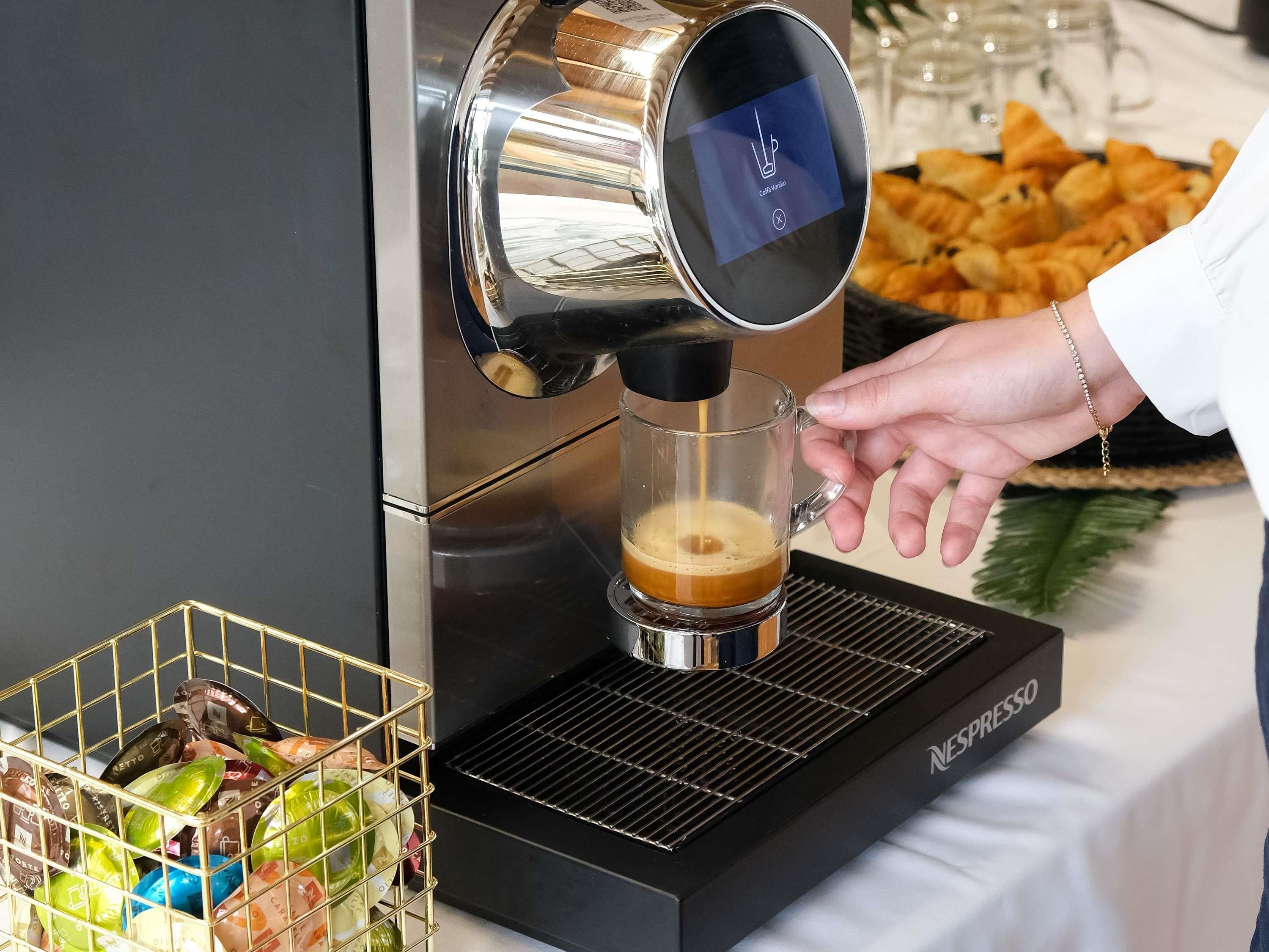 Una máquina de café sirviendo café en una taza de vidrio.