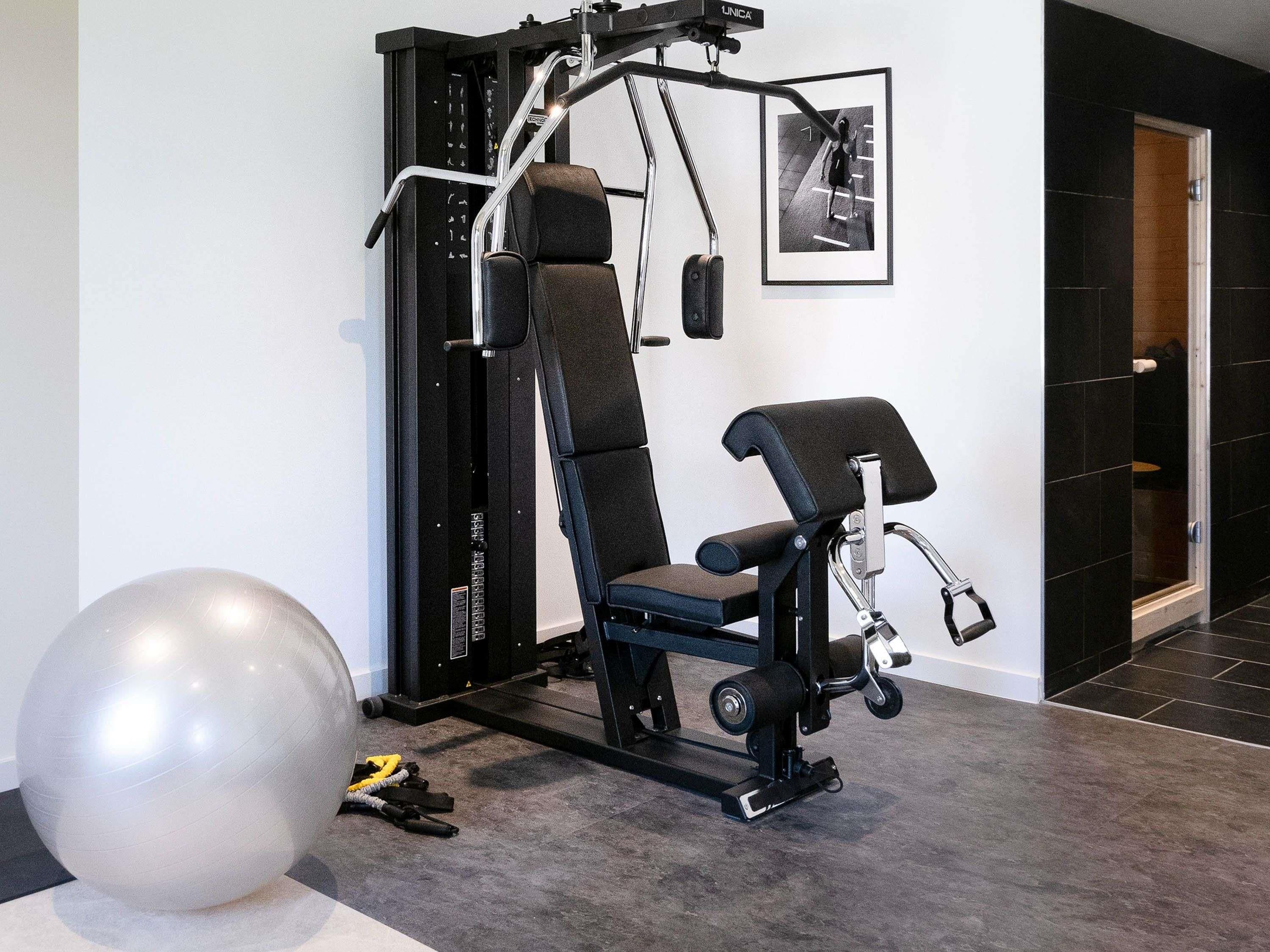 Un gimnasio en casa con barra de dominadas, banco de pesas y pelota de ejercicios.