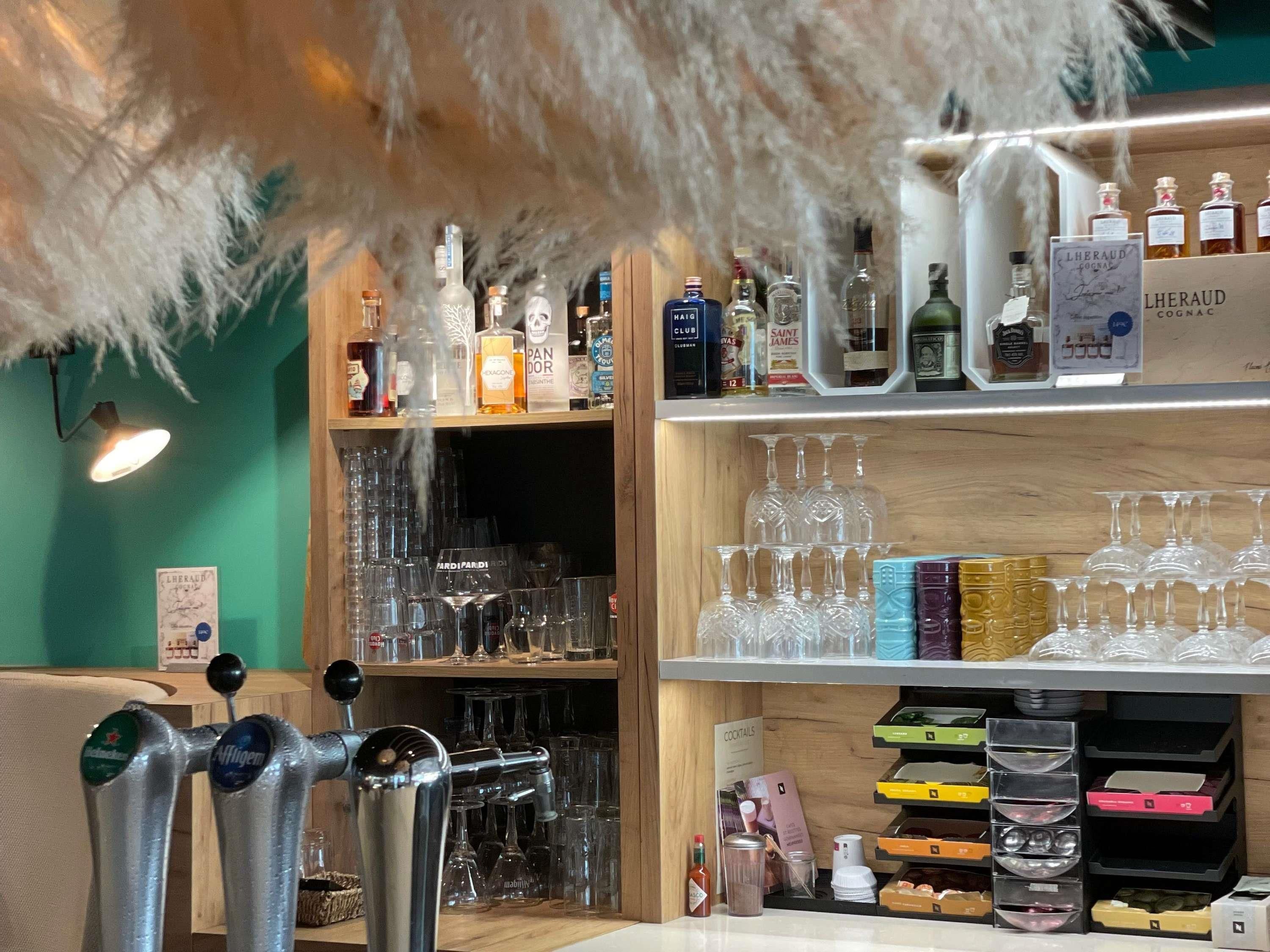 A bar area with multiple shelves of liquor bottles, glasses, and a beer tap.