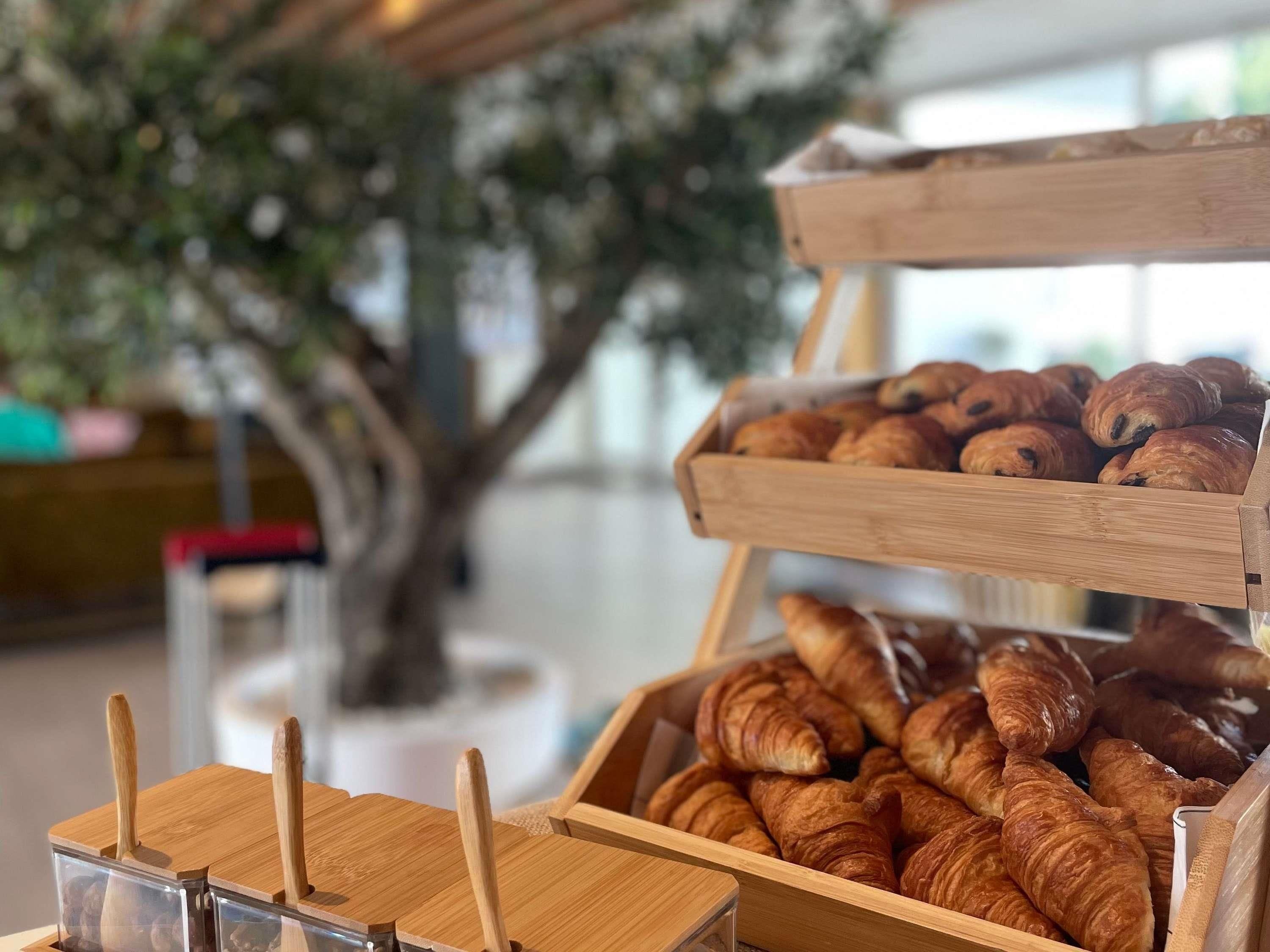 Une vitrine de boulangerie présentant des croissants et un présentoir en bois avec des ustensiles.